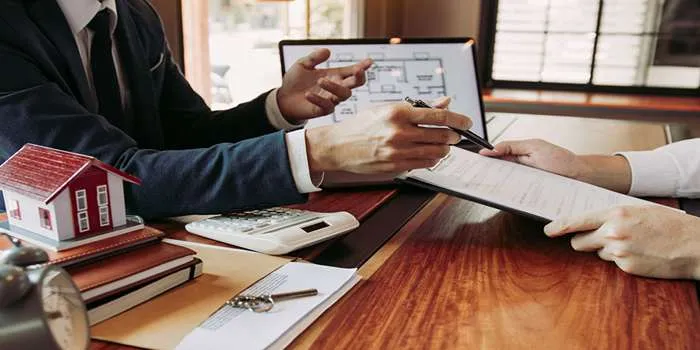 اصطلاحات رایج در زمینه املاک که باید با آنها آشنا شوید _ تصویر دستهای فردی که با خودکار در حال نشان دادن نوشته ای به فرد دیگر است.