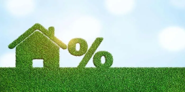 مالیاتهای مربوط به املاک و مستغلات _ تصویری از یک خانه با چمن سبز و علامت درصد در کنار آن