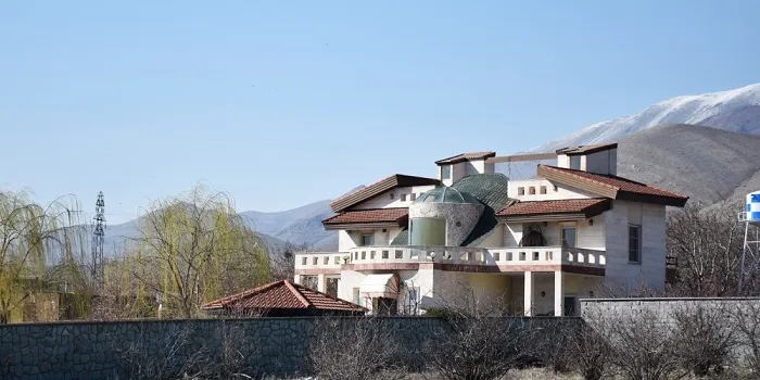 تصویری از یک خانه ویلایی سفید با شیروانی قهوه ای